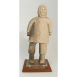 AN INUIT WHALE BONE CARVING OF AN ESKIMO MAN standing and mounted to a perspex and wood base, the