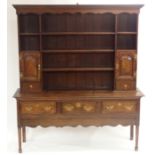AN OAK DRESSER the three tier plate rack with scalloped canopy above a pair of panelled doors, the