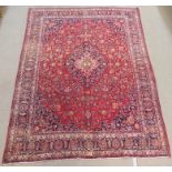 A RED GROUND MESHED RUG with blue central medallion and matching spandrels and borders, 295cm x