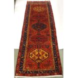 A RED GROUND KAREJEH RUNNER with five central lozenges with geometric designs and stylised