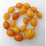 A STRING OF AMBER COLOURED BEADS largest bead approx 2.8cm x 2.3cm smallest 1.6cm x 1.2cm, length (