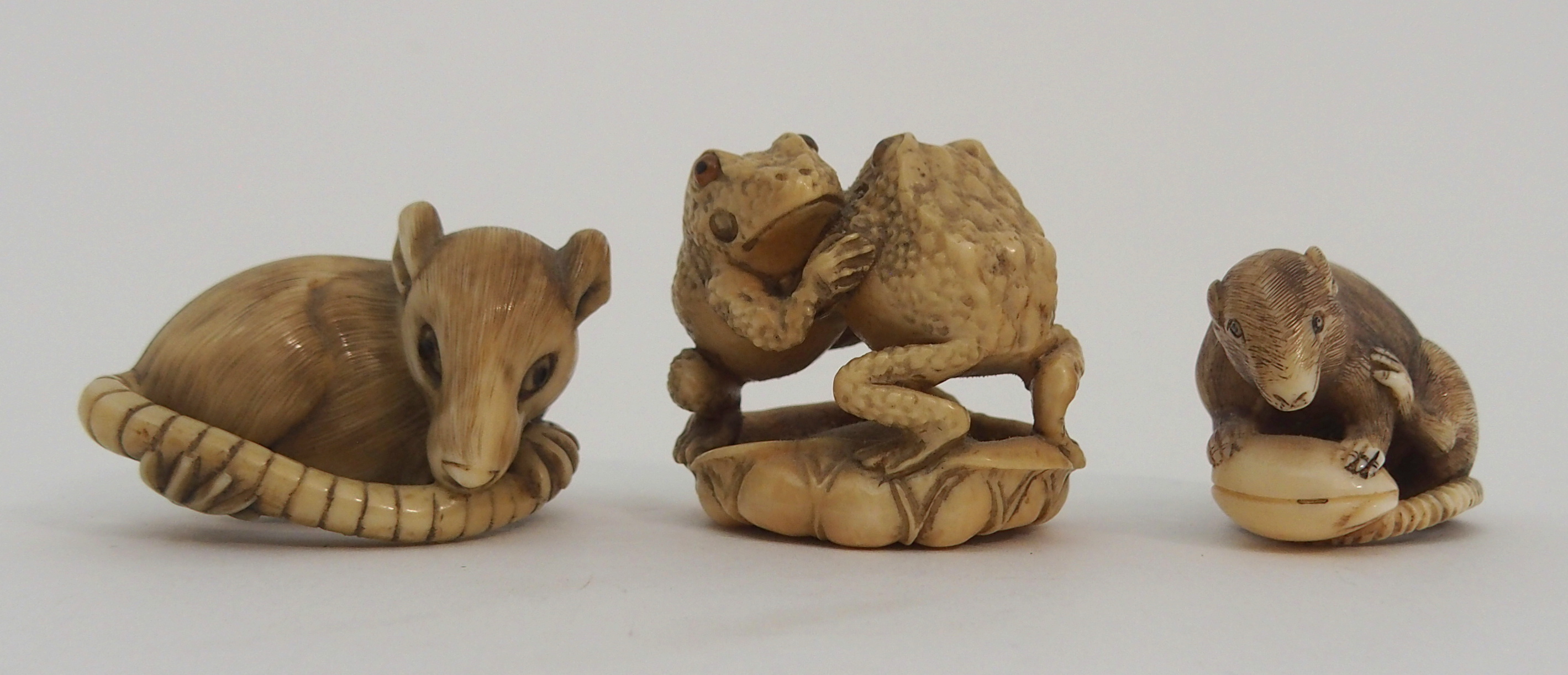 THREE JAPANESE IVORINE NETSUKE one as a rat holding a nut, signed, 3cm high, another chewing tail,