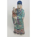 A CANTON FIGURE OF AN OFFICIAL HOLDING A CHILD standing and wearing kimono set with crane roundels