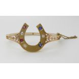 A YELLOW METAL DIAMOND, RUBY AND SAPPHIRE HORSESHOE BANGLE set with estimated approx 0.22cts of