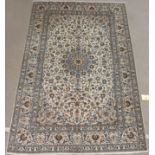 A CREAM GROUND FINE KESHAN LAMBS WOOL RUG with blue central medallion, signed, 204cm x 306cm