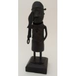 A BENIN BRONZE FIGURE OF A WARRIOR standing and holding ceremonial sword and on a square base with