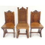 A PAIR OF VICTORIAN GOTHIC OAK HALL CHAIRS 93cm high and another, 106cm high (3) Condition Report: