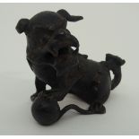 A CHINESE BRONZE SHISHI modelled seated and holding a brocade ball, 17th/18th Century, 6.5cm high
