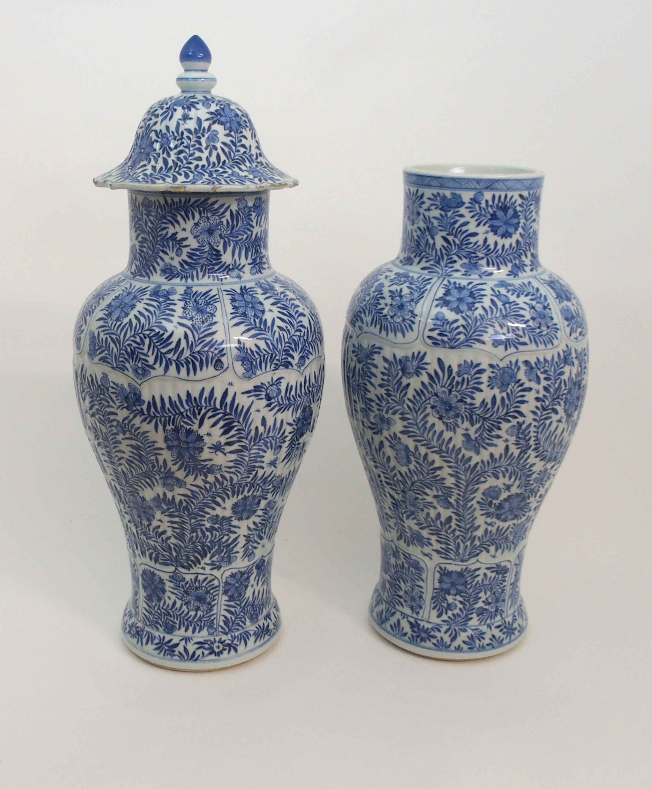 A PAIR OF CHINESE BLUE AND WHITE MOULDED BALUSTER VASES AND A COVER painted with panels of flowers