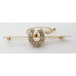 A 15CT GOLD DIAMOND SET HORSESHOE BAR BROOCH set with old cut diamonds to an estimated approximate