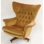 A G-PLAN 6250 "WORLD'S MOST COMFORTABLE CHAIR" wingback rocking swivel armchair with teak base in