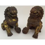 A PAIR OF CHINESE GILT METAL MODELS OF SHISHI each seated and standing on a brocade ball, late