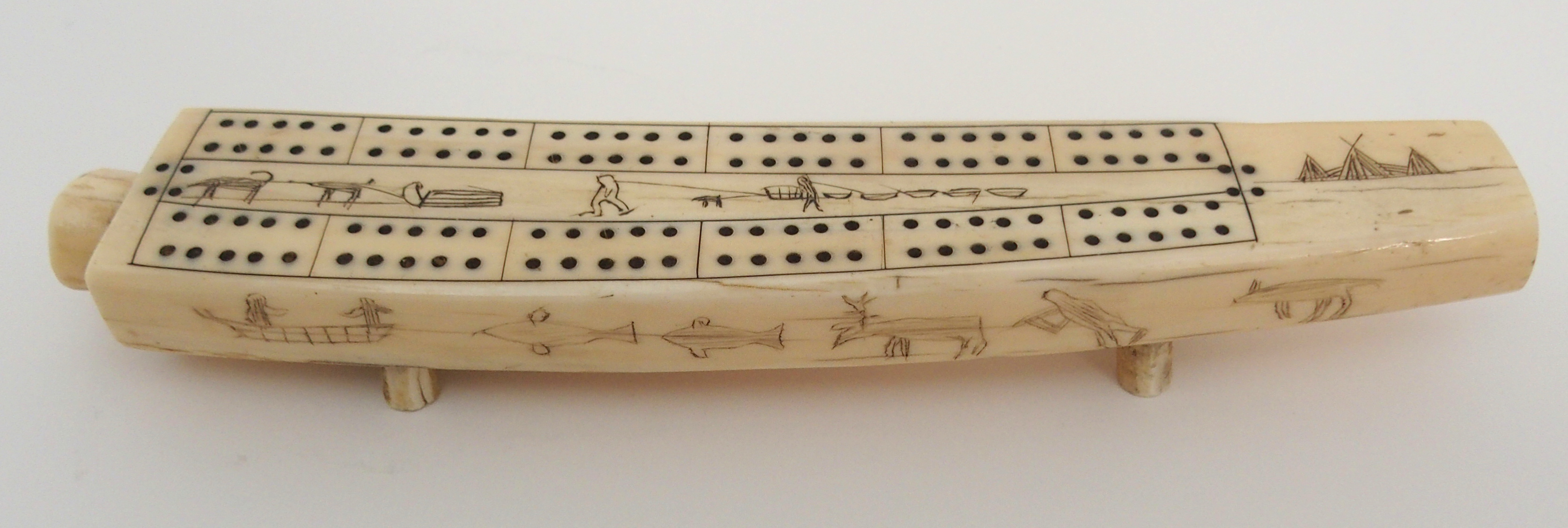 AN INUIT WALRUS TUSK CRIBBAGE BOARD the top with twelve pierced marker sections, divided by Eskimos,