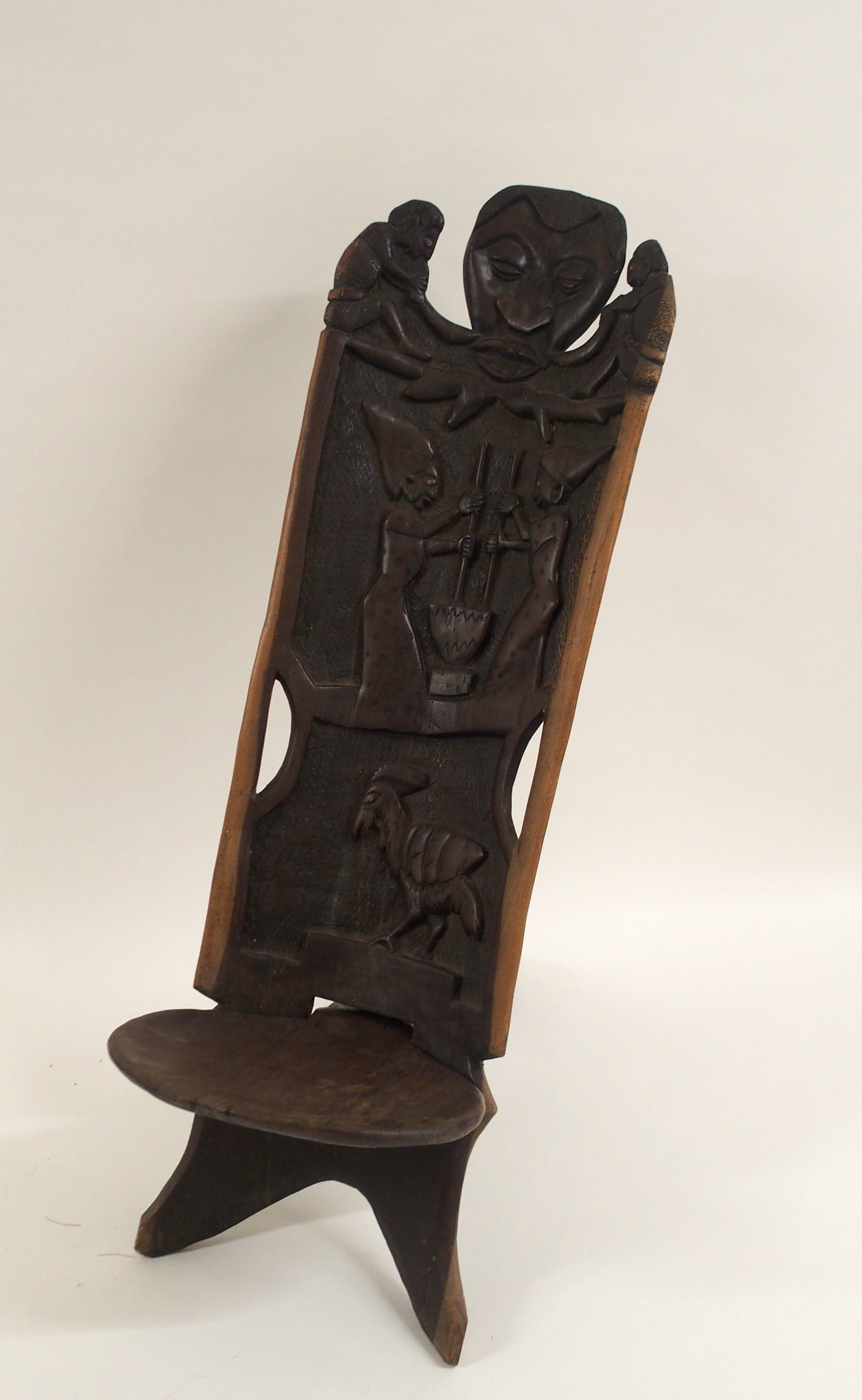 AN AFRICAN CARVED BIRTHING CHAIR the back with face mask flanked by two figures, above two women