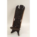 AN AFRICAN CARVED BIRTHING CHAIR the back with face mask flanked by two figures, above two women