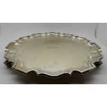 A silver salver, Sheffield 1933, of circular form with scalloped edge on three scrolling feet,