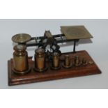 A set of Samson Modan & Co brass postal scales with associated weights on oak base, 31.5cm wide
