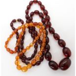 A long string of cherry amber coloured beads, length 84cm, together with a string of orange amber