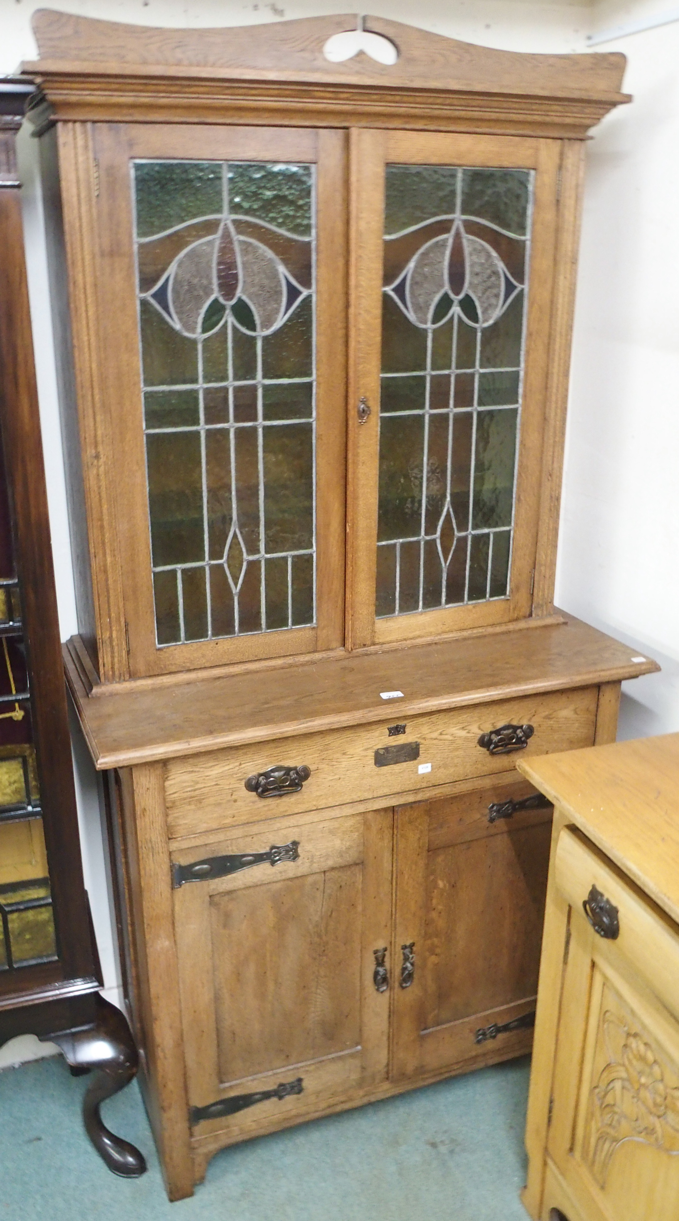 An oak Arts and Crafts cabinet with stained glass doors over a base with single drawer and two