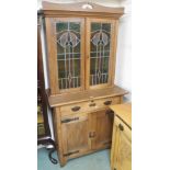 An oak Arts and Crafts cabinet with stained glass doors over a base with single drawer and two