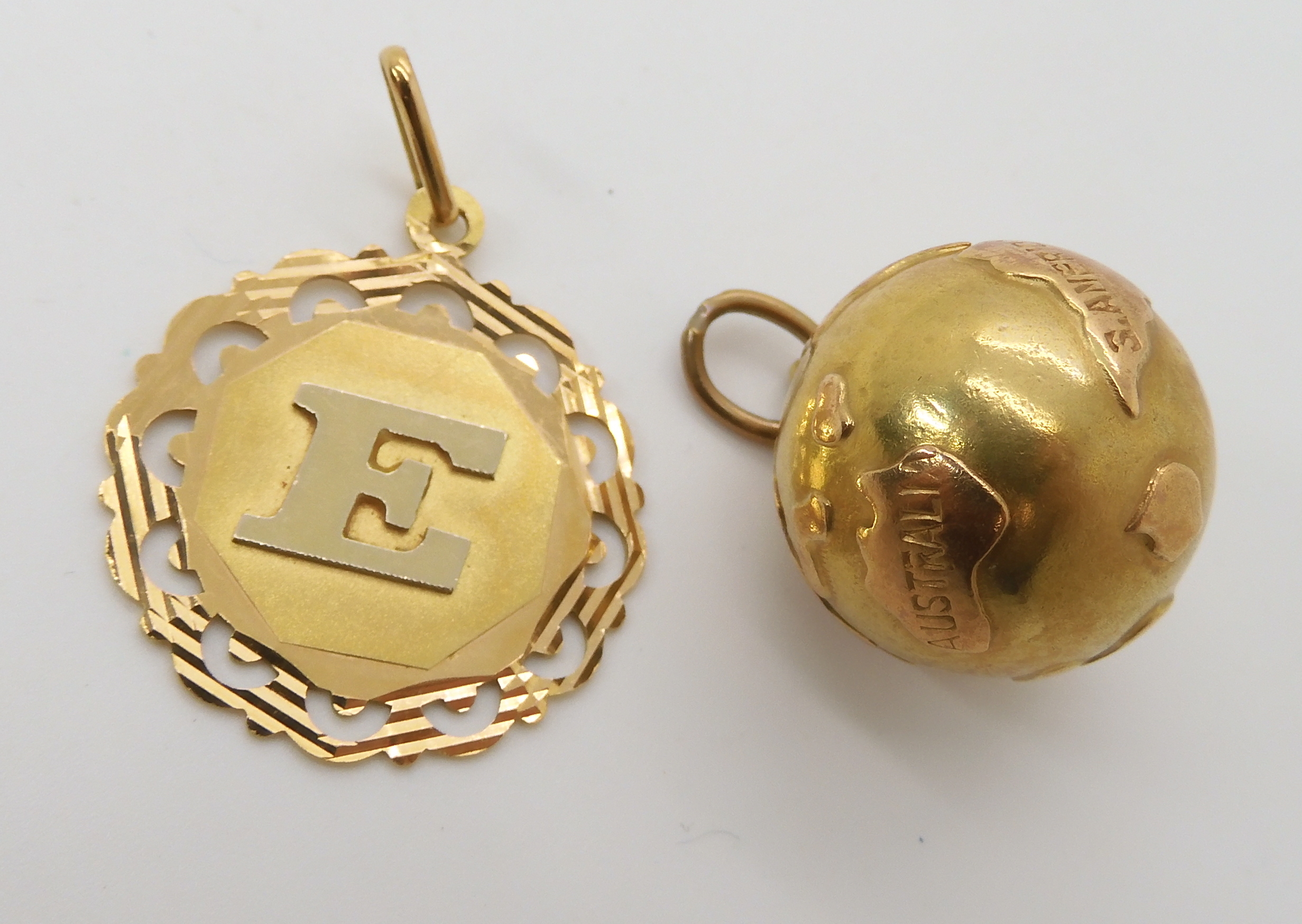 A bright yellow metal world pendant stamped 750, together with an 18ct gold pendant combined