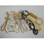 A collection of vintage costume jewellery to include a gold plated cuff bangle, glass beads,