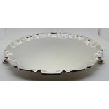 A silver salver, Birmingham 1961, of circular form with scalloped edge and three scrolling feet,