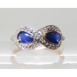 A 9ct gold infinity designed sapphire and diamond accent ring, head size 8mm x 16.2mm, finger size