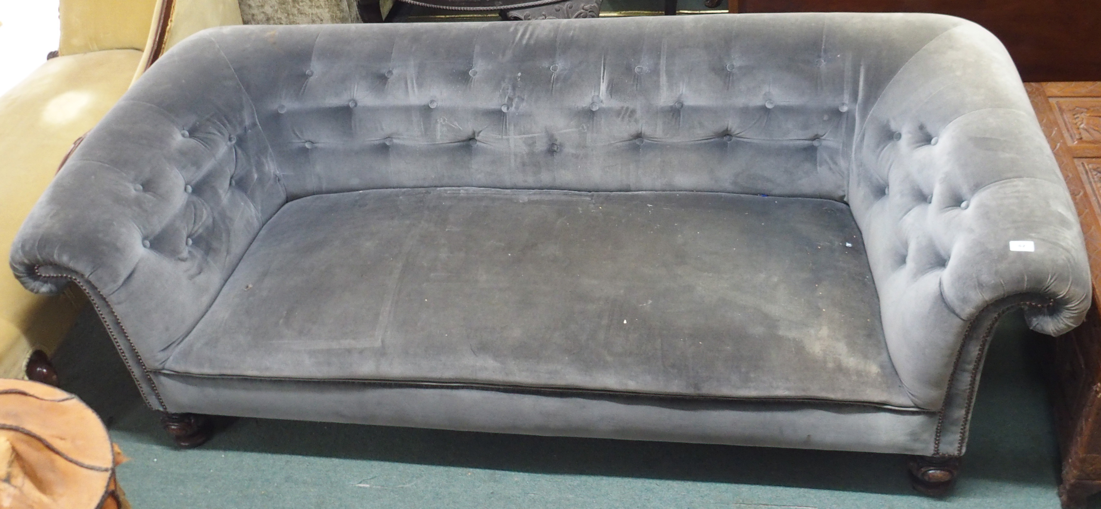 A Victorian grey upholstered Chesterfield three seater sofa with carved feet, 70cm high x 220cm wide