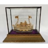 A Eastern gilt metal model of a motor boat in perspex and gesso case, the boat 30cm long Condition