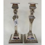 A pair of silver plated candlesticks, the removable drip pans on square tapering stems with ribbon