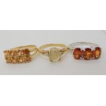 A 9ct gold three stone mandarine garnet ring size N1/2, a 9ct gold tangarine garnet cluster ring,