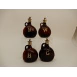 A SET OF FOUR BROWN GLASS LIQUOR DECANTERS each with EP mounts and labels including G, W, R & B,