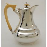 A SILVER HOT WATER POT by Emile Viner, Sheffield 1934, of oval baluster shape with scrolling ivory