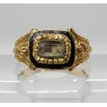 A BRIGHT YELLOW METAL EARLY VICTORIAN MOURNING RING with glazed hair panel and black enamel to the