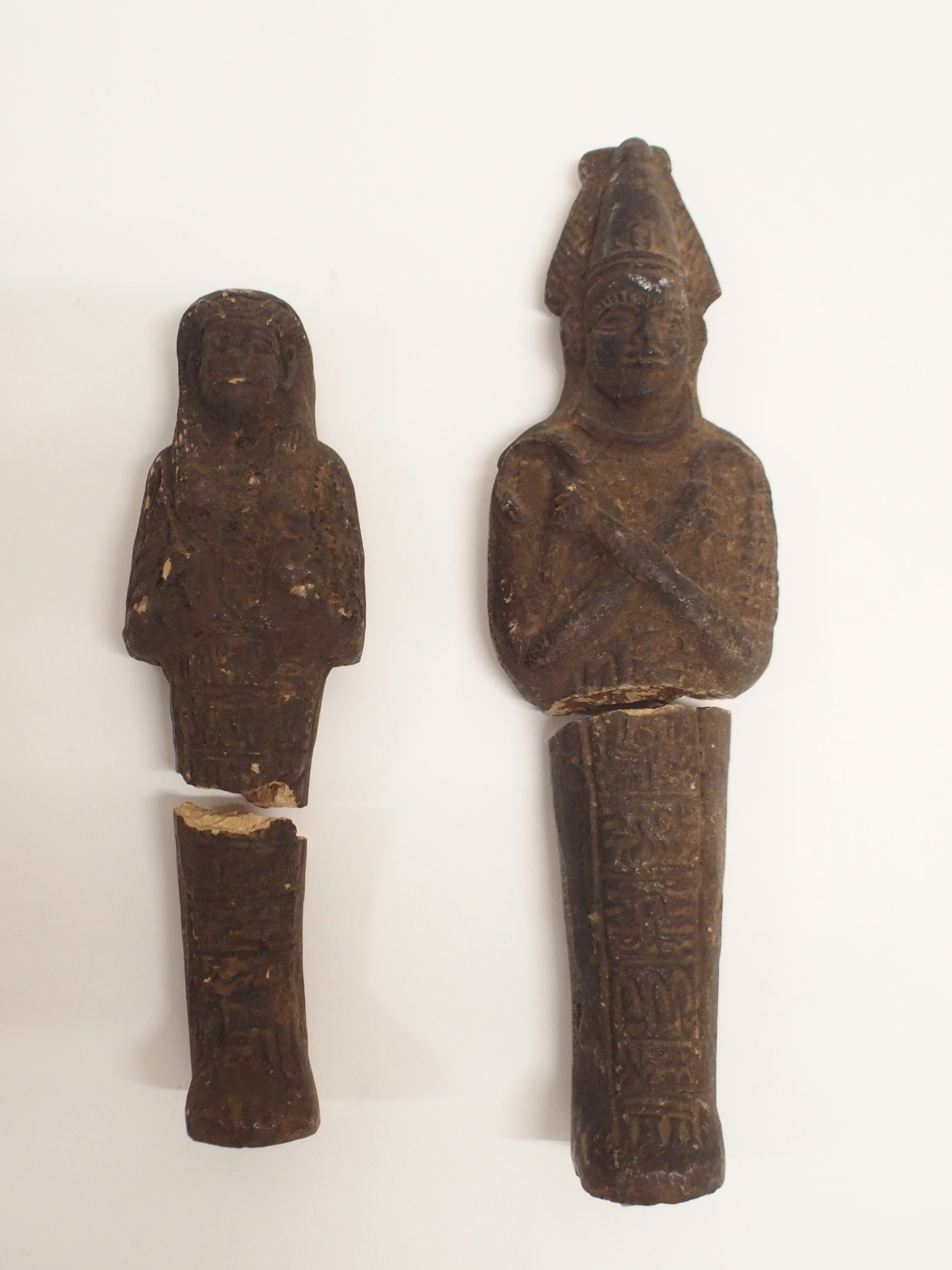 TWO EGYPTIAN SHABTI each holding crook and flail, 15 and 20cm high Condition Report: both broken