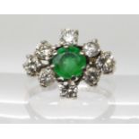 AN 18CT WHITE GOLD EMERALD AND DIAMOND CLUSTER RING the central emerald is approx 5.6mm x 3.8mm