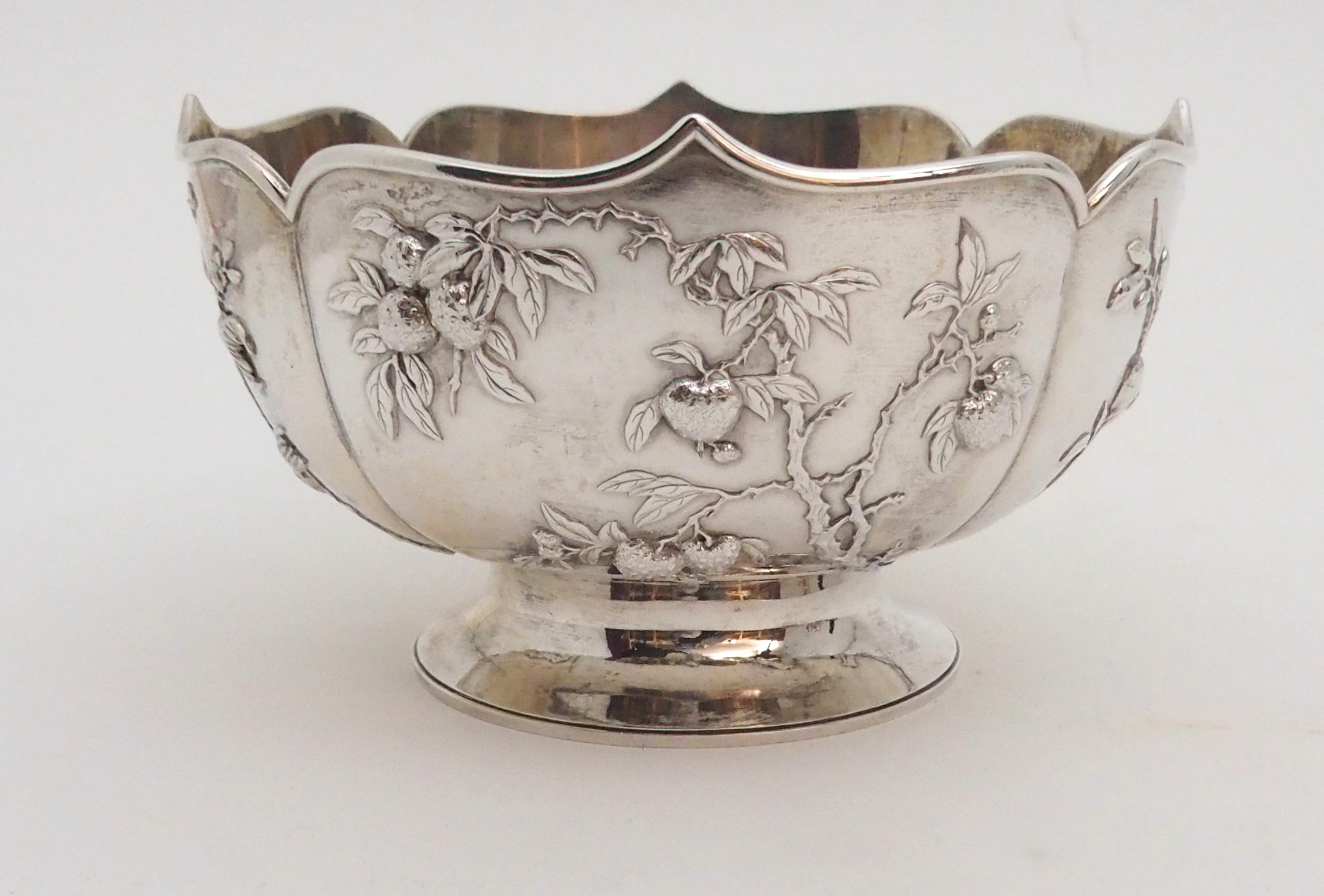 A CHINESE SILVER LOBED BOWL decorated with panels of fruit, beneath a folded rim and stamped, ZEEWO