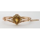 A 9CT GOLD VINTAGE BANGLE set with a heart shaped citrine surmounted with a wire work lover's
