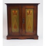 A MAHOGANY ART NOUVEAU SMOKER CABINET with hinged panel doors, pipe rack and three drawers with