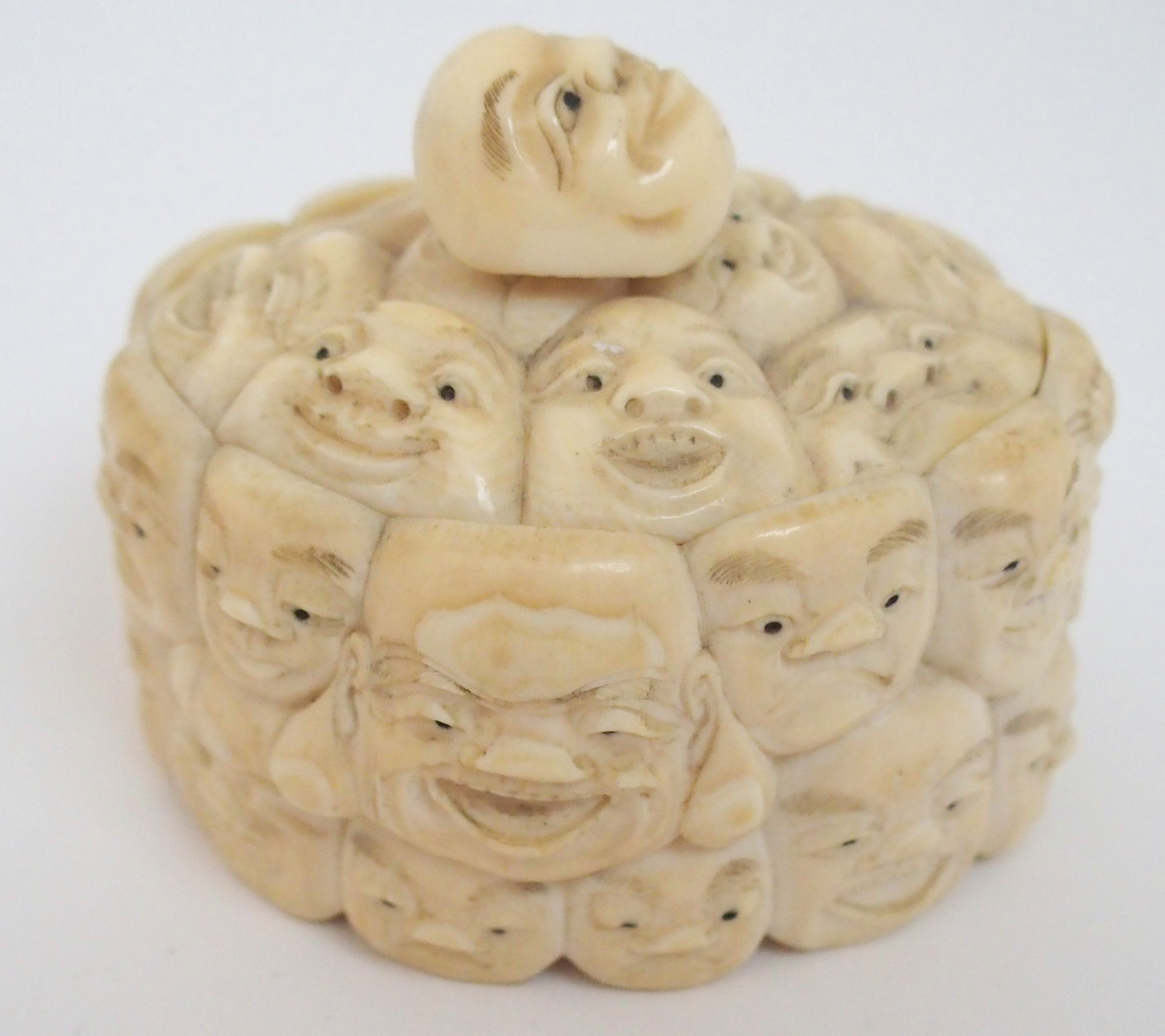 A JAPANESE IVORY OVAL MASK BOX AND COVER carved with many face masks, the cover with mask finial, - Image 7 of 14