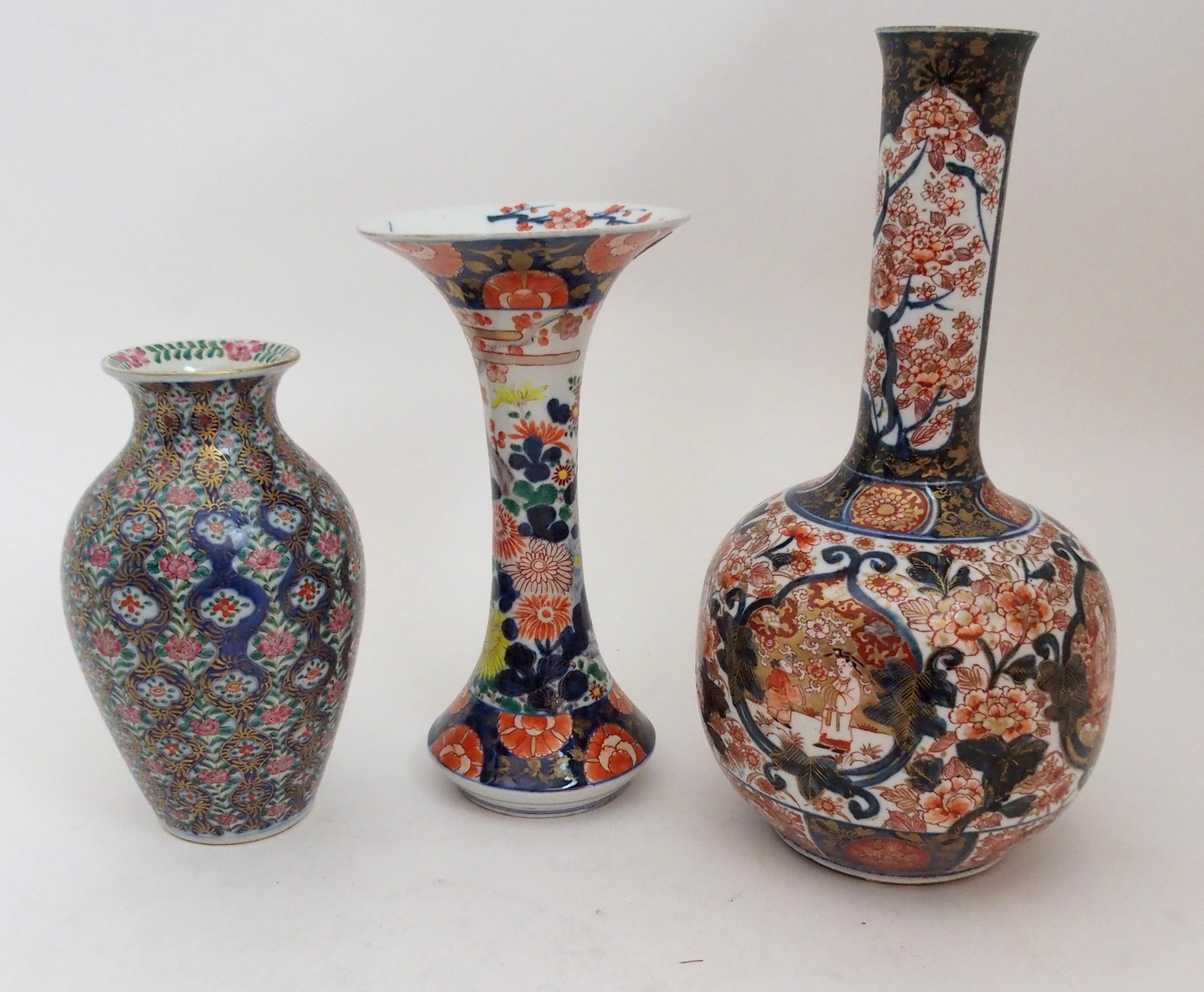 AN IMARI BOTTLE SHAPED VASE painted with figures in gardens surrounded by foliage and detailed in