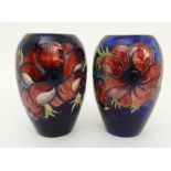 TWO SIMILAR MOORCROFT ANEMONE PATTERN VASES the dark blue ground with tubelined red and purple