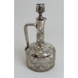 A CLEAR GLASS DECANTER bottle shaped, the body overlaid in unmarked silver flowerheads and