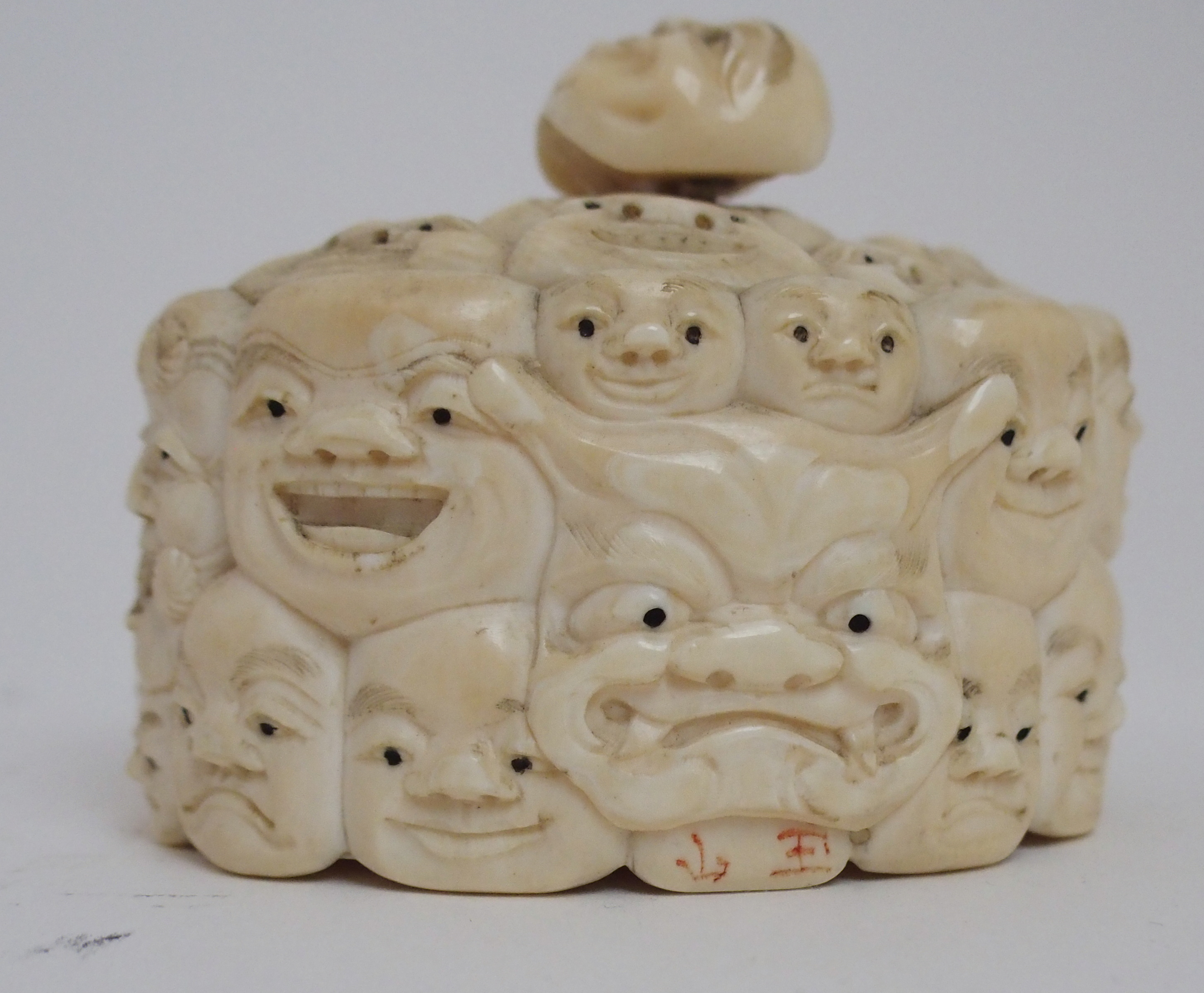 A JAPANESE IVORY OVAL MASK BOX AND COVER carved with many face masks, the cover with mask finial, - Image 9 of 14