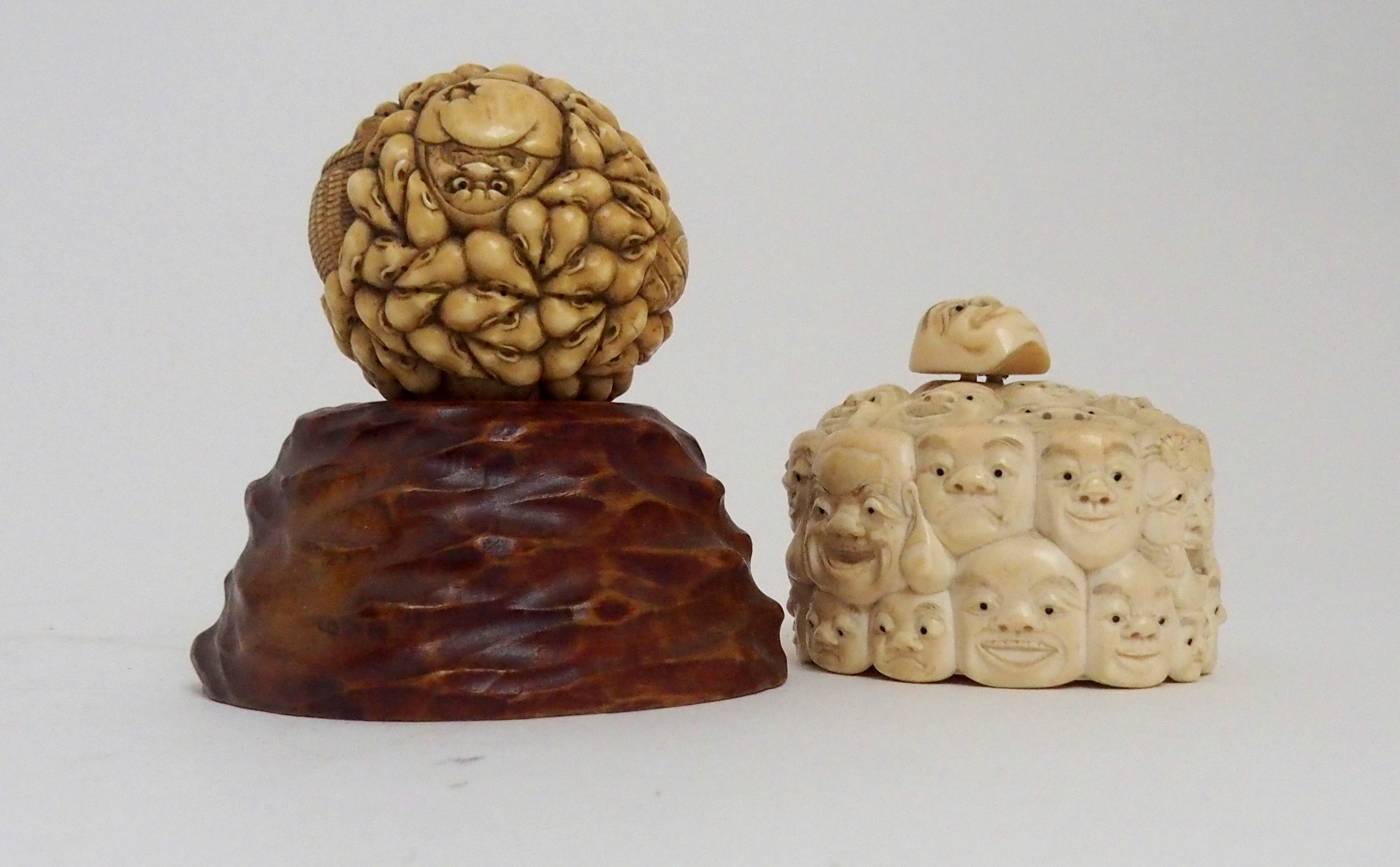 A JAPANESE IVORY OVAL MASK BOX AND COVER carved with many face masks, the cover with mask finial,