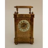 A FRENCH BRASS CASED CARRIAGE CLOCK with gilded fret panels to sides and front, with clear door