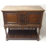 A FRENCH WALNUT LIVERY CUPBOARD the hinged top enclosing a deep and shallow recess, the front carved