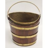 A GEORGE III TEAK AND BRASS PEAT BUCKET with swing handle and liner, bound with three straps, 34cm