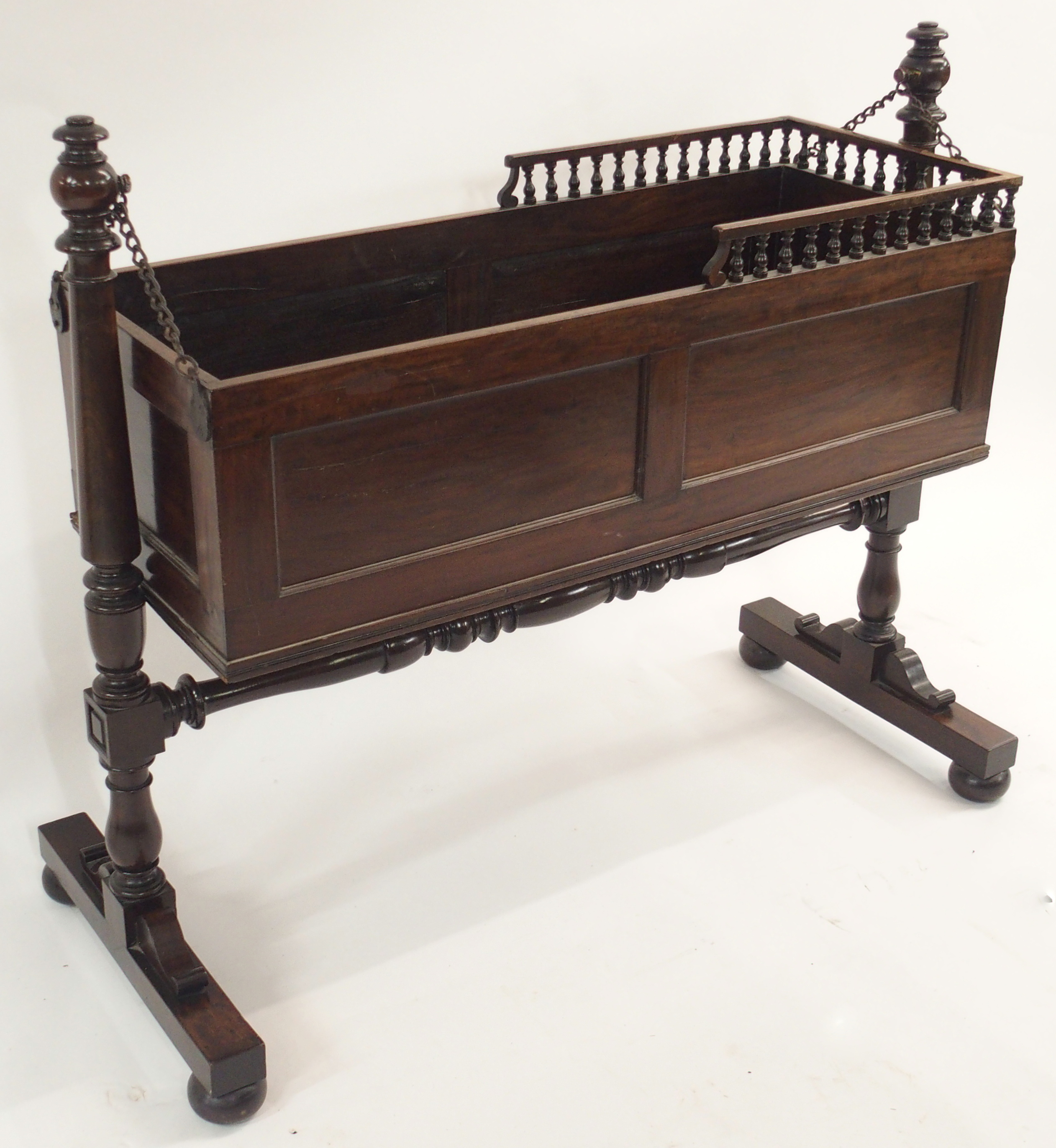 AN EARLY 19TH CENTURY MAHOGANY CRIB the panelled box with three quarter baluster gallery on chain